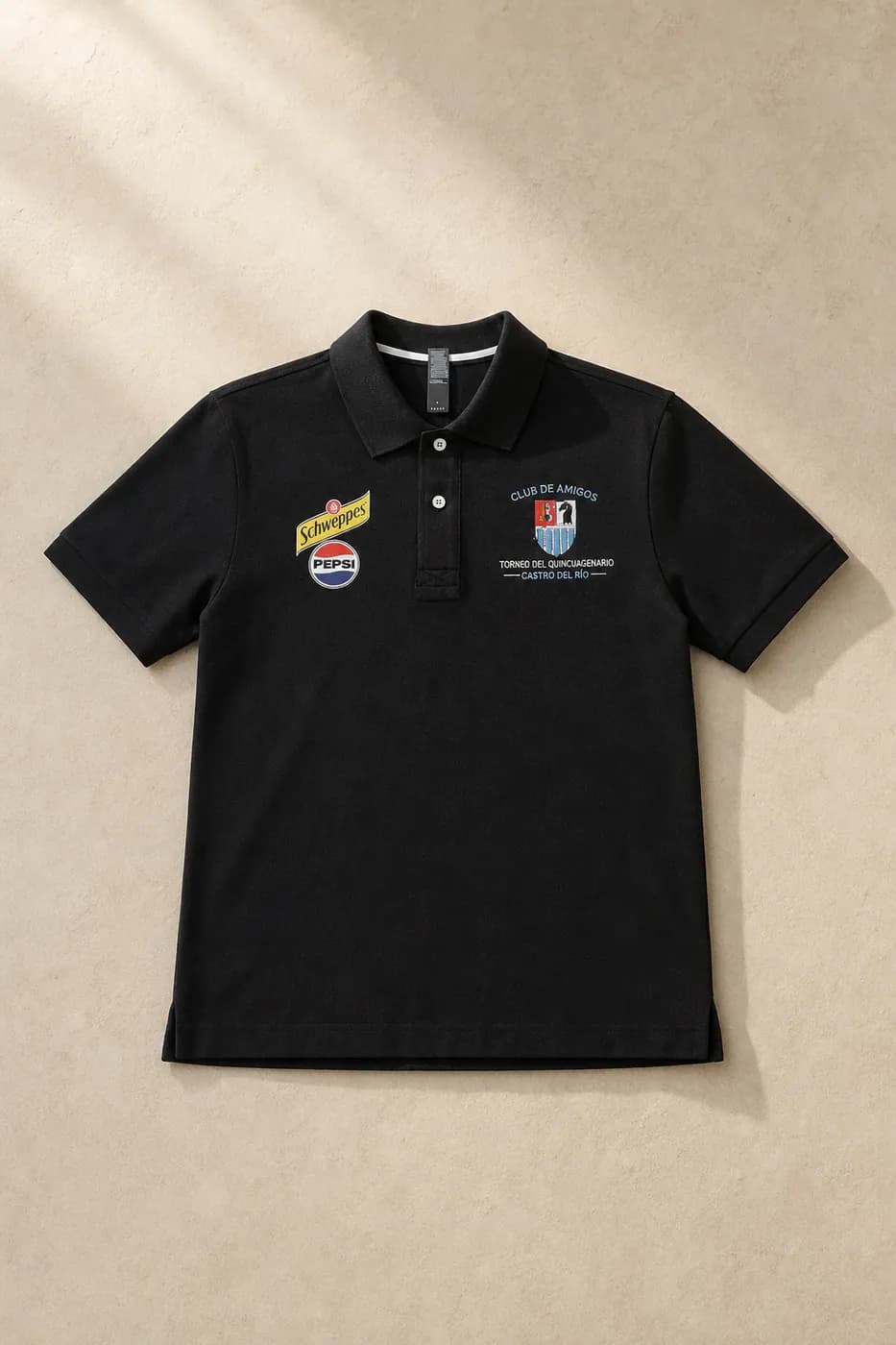 Polo negro bordado con el escudo de un torneo y los logotipos de sus patrocinadores